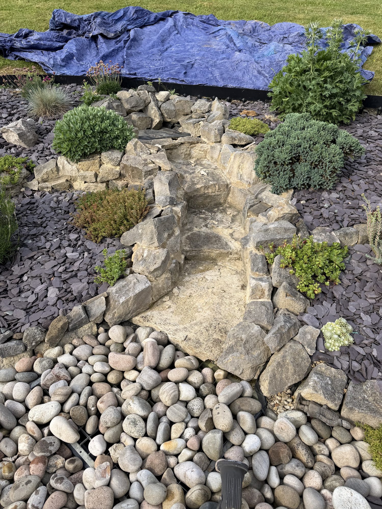 Natural stone rockery with a cascading waterfall, alpine planting and a slate-and-cobble apron