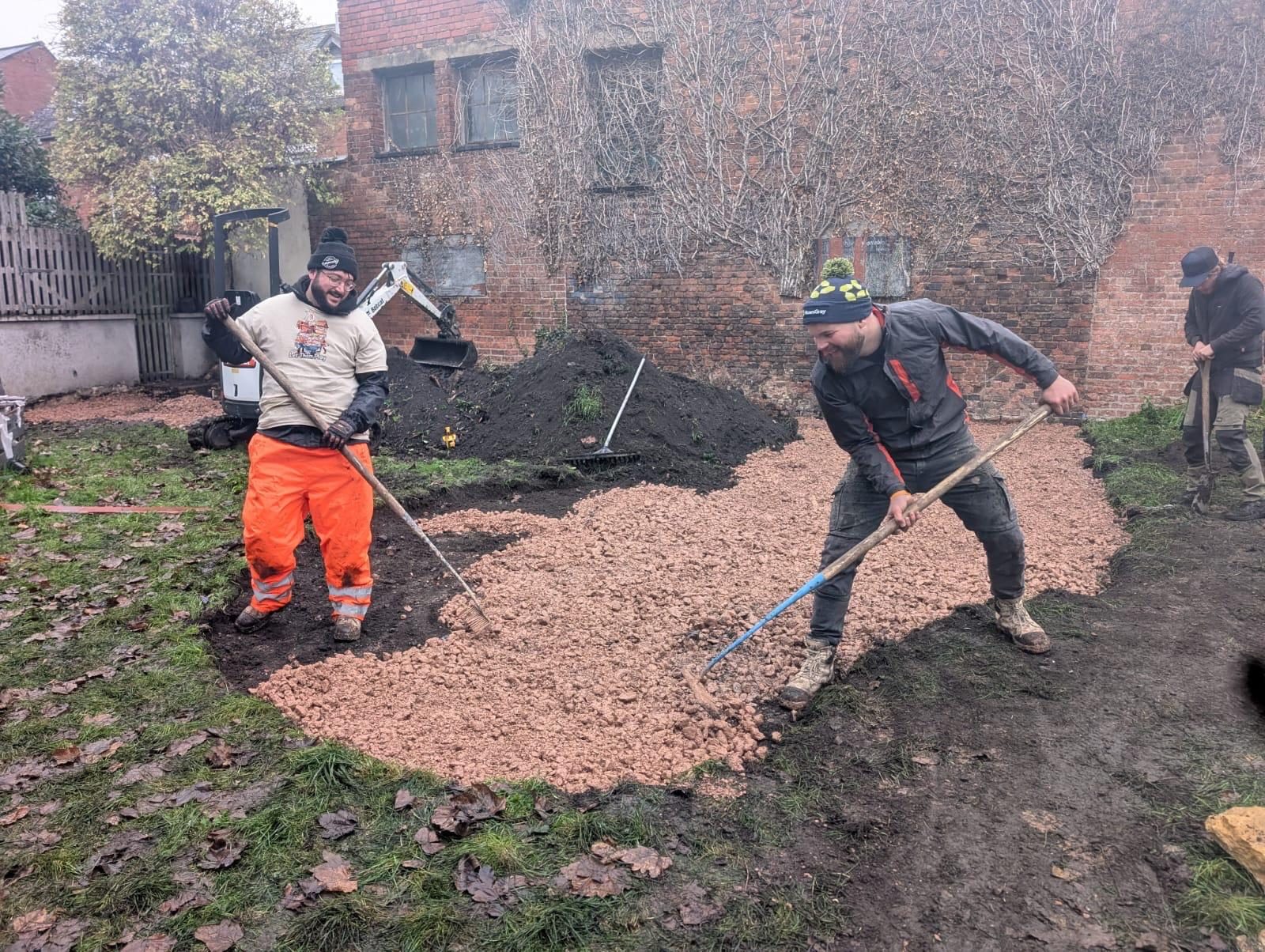 Two landscapers spreading and levelling the sub-base during the play garden build