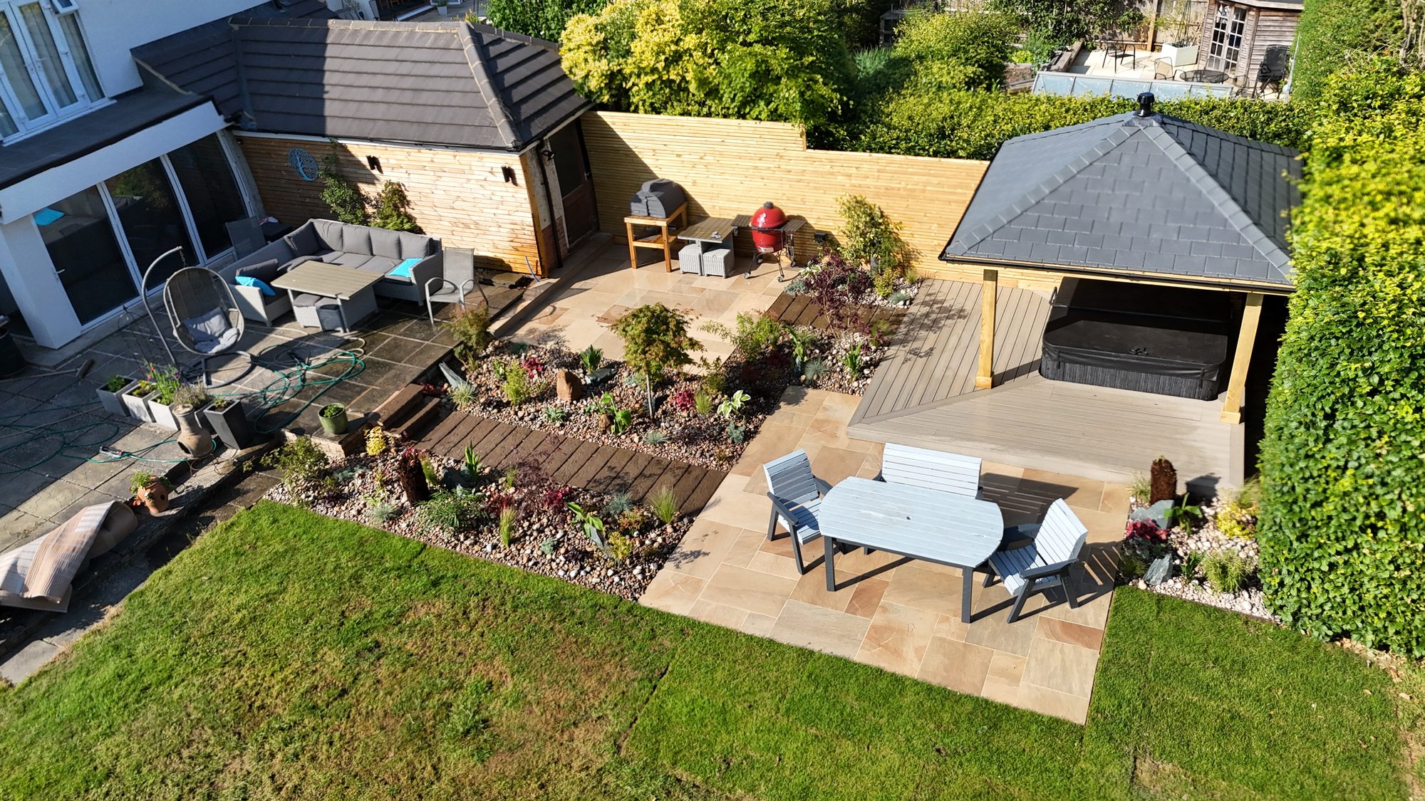 Aerial view of a landscaped rear garden with patio, decking and planted beds