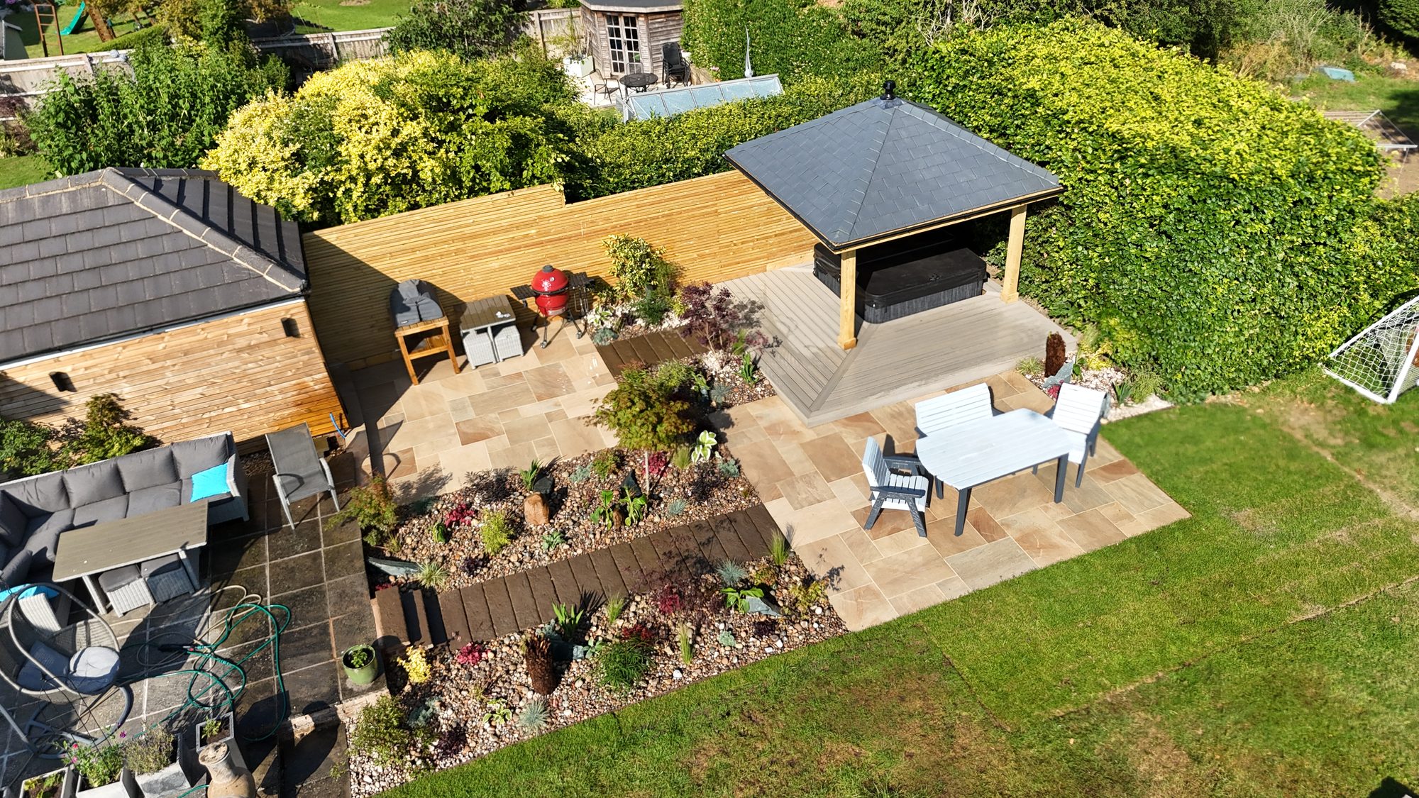 Aerial view of a completed Gardenscape garden design and build, with a timber garden room, riven sandstone patio, composite decking and richly planted beds