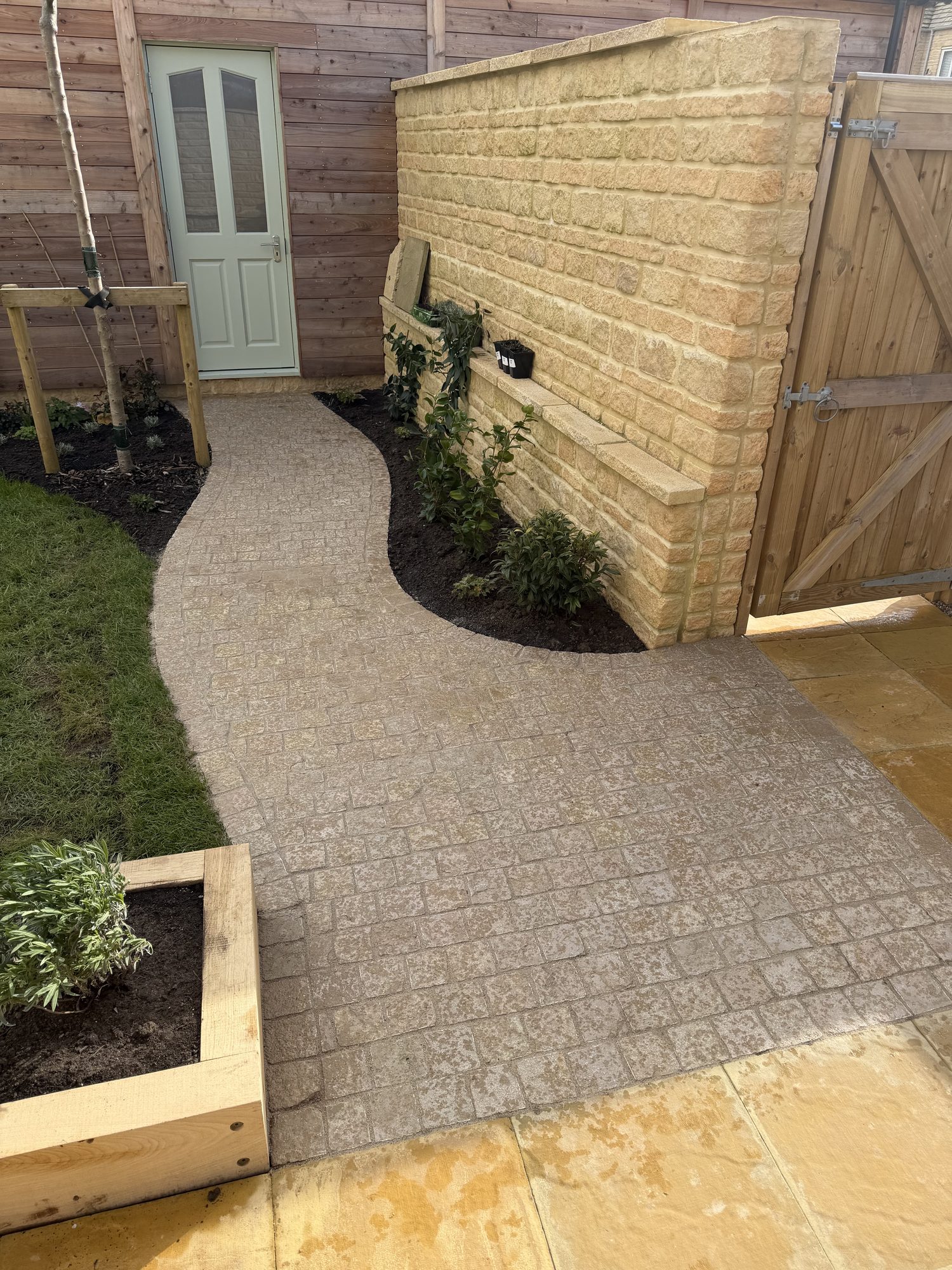 Imprinted concrete path leading to a door beside a stone-clad wall
